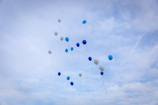 Witte en blauwe ballonnen gevuld met helium stijgen op tegen een bewolkte lucht