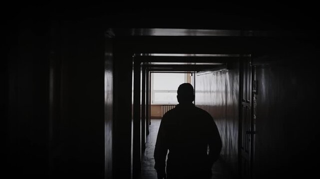 The silhouette of a doctor walking down a dark hospital corridor toward the light. A symbol of hope and healing, faith in miracles, a doctor saving lives, a diagnosis not a death sentence.