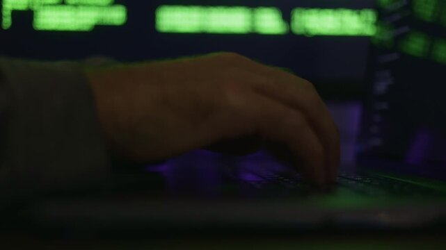 Developer working on colorful keyboard, Person intensely engaged in scripting with illuminated keyboard setup, Individual dedicated to coding tasks using vibrant backlit keyboard in busy environment