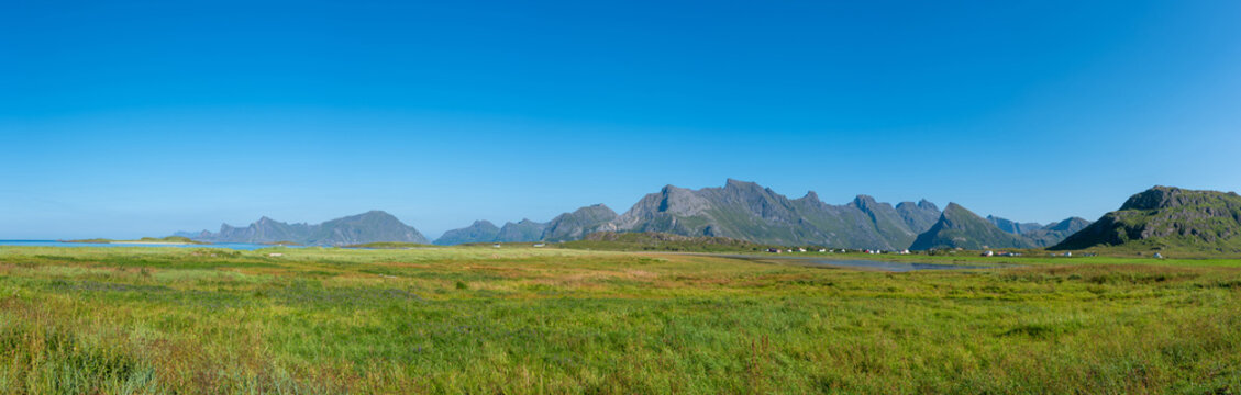 Landscape near Fredvang with the Norwegian Sea, an impressive mountain backdrop, and the striking peak of Volandstind. Lofoten in Norway.