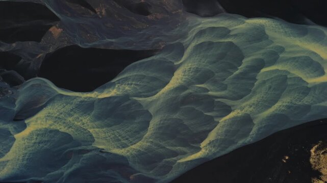 Aerial view of the braided glacial river system creating striking patterns on the dark landscape, a surreal display of nature's artistry, Selfoss, Iceland.