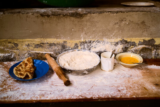 Rustic kitchen scene with flour, rolling pin, and bread on a wooden surface. Kigali, Rwanda
