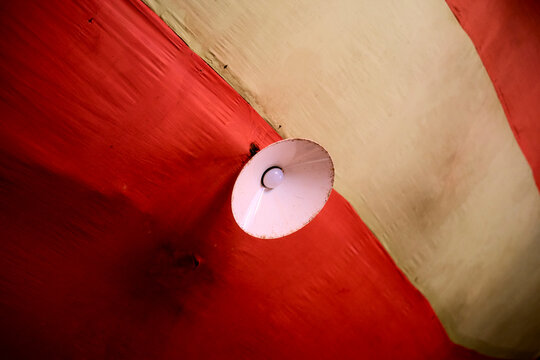 A white lampshade contrasts against a red and cream striped ceiling. Kigali, Rwanda
