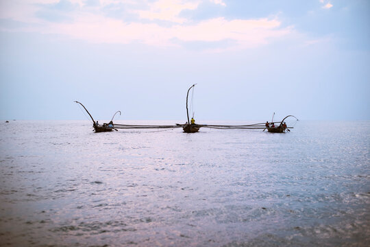 Three fishing boats with large nets on a calm sea under a pastel sky at dusk. Kigali, Rwanda