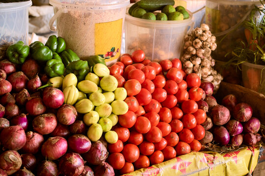 Fresh produce assortment with tomatoes, onions, peppers, and garlic at a market stall. Kigali, Rwanda
