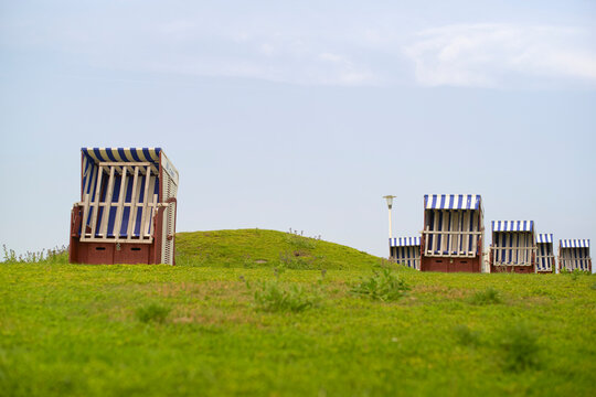 Striped beach chairs on a hill under a blue sky with scattered clouds. North Sea, Belgium