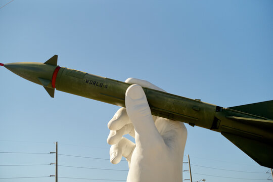 Giant white hand sculpture holding a green missile against a clear blue sky. Miami, Florida, USA