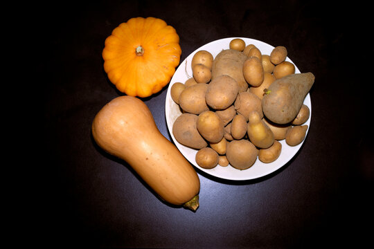 Assorted squashes and potatoes on a dark background with a white bowl.   Belgium