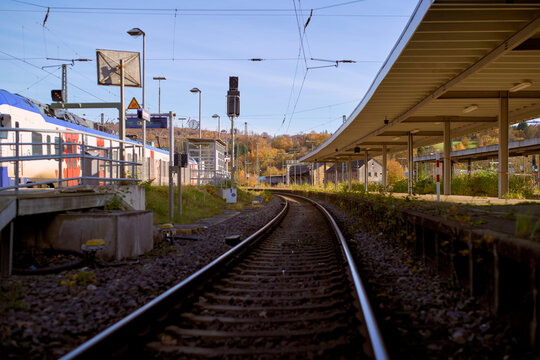 Railway tracks leading through an empty train station on a clear, sunny day. Germany