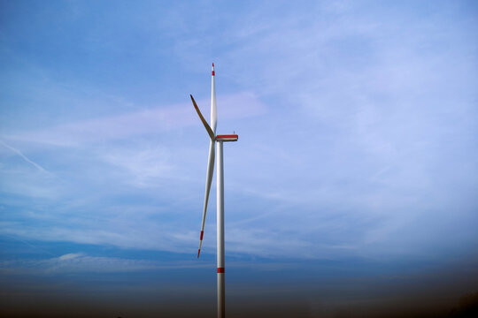 A single wind turbine stands against a vast clear blue sky with minimal cloud coverage. Germany