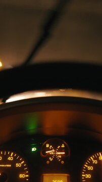 Behind the wheel driving at night in rain with dashboard in focus