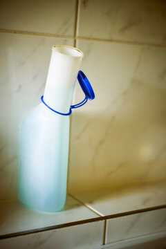 Plastic bottle for urination with blue flip cap sitting on a tiled bathroom shelf. Germany