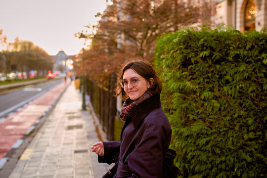 Young woman with glasses smiling on a city street during sunset. Germany