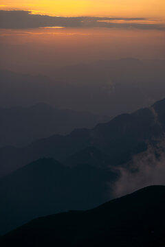 Sunset over hazy mountain range with layers of peaks and clouds in the distance Mountains of Ta Xua, Bac Yen District, Son La, Vietnam