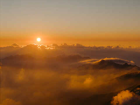 Breathtaking sunrise over a range of misty mountains with orange and golden hues. Ta Xua, Bac Yen District, Son La, Vietnam