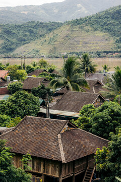 Rustic wooden houses surrounded by lush greenery with mountains in the background. Muong Lay, Thi xa Muong Lay, Dien Bien, Vietnam