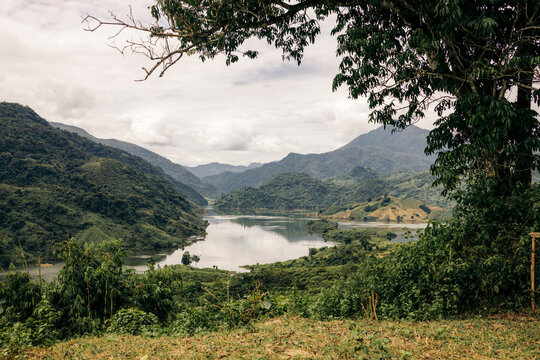 Lush mountainous landscape with a serene river and dense green foliage under a cloudy sky.   Muong Te District, Lai Chau, Vietnam