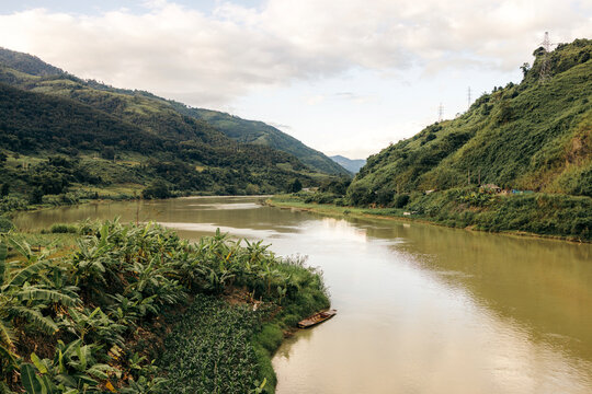 Serene river winding through lush green hills under a partly cloudy sky. Muong Te District, Lai Chau, Vietnam