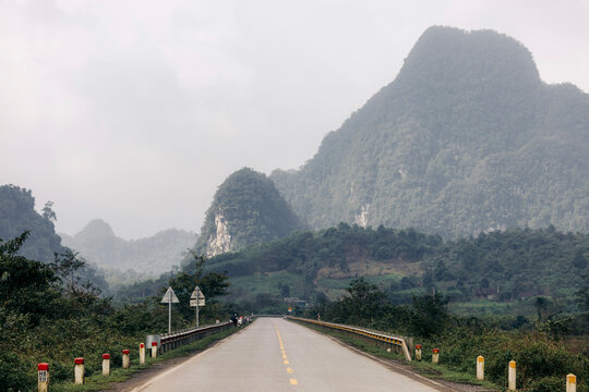 Long road leading towards misty green mountains under a cloudy sky. Son Trach, Bo Trach District, Quang B&Iuml;nh, Vietnam