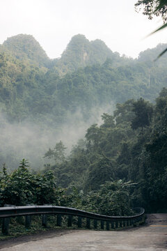 Misty mountain road winding through lush green forest with distant peaks in the background. Son Trach, Bo Trach District, Quang B&Iuml;nh, Vietnam
