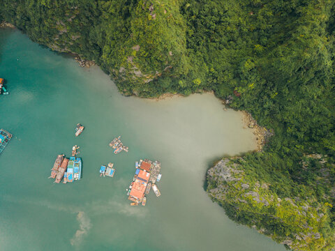 Aerial view of boats on a turquoise sea near lush green forested cliffs. Lan Ha Bay, Cat Ba, Vietnam