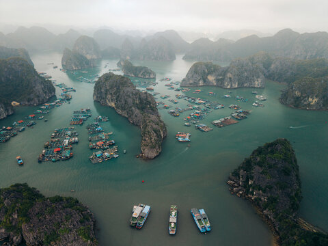 Aerial view of floating fishing villages and boats amidst scenic limestone islets and emerald waters. Lan Ha Bay, Cat Ba, Vietnam