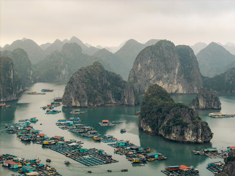 Floating fishing village with limestone karsts in a calm bay surrounded by misty mountains. Lan Ha Bay, Cat Ba, Vietnam