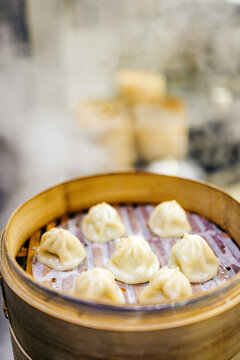 Steaming dumplings in a bamboo basket with gentle steam rising in a kitchen setting. Chiayi City, Taiwan