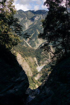 A breathtaking view of a lush valley framed by tall trees on a steep mountainside. Yuli Township, Hualien County, Taiwan
