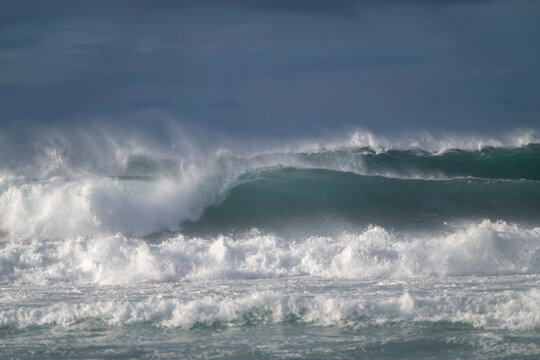 Powerful ocean waves crash under a stormy sky. Paia, Hawaii, USA
