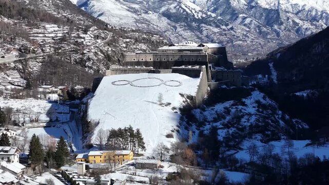 Aerial view of Forte di Exilles, a snowy fortress embraced by mountains, creating a stark contrast between stone and snow, Exilles, Piemonte, Italy.