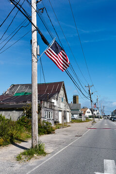 A small town street with weathered buildings and an American flag on a utility pole. Marshfield, USA