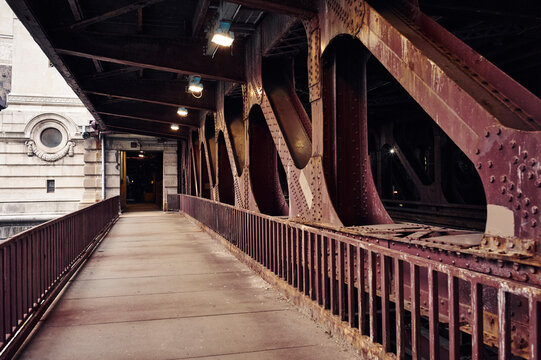 Old iron bridge walkway with riveted beams and city building in background. Chicago, Illinois, USA
