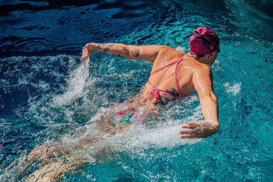 Swimmer in a pool performing the butterfly stroke with water splashing around. USA