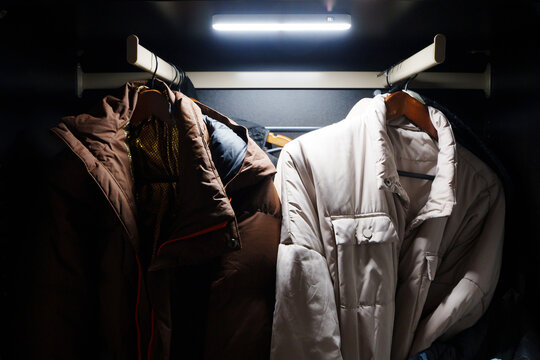 Motion sensor LED lamp illuminates clothes in a dark closet space