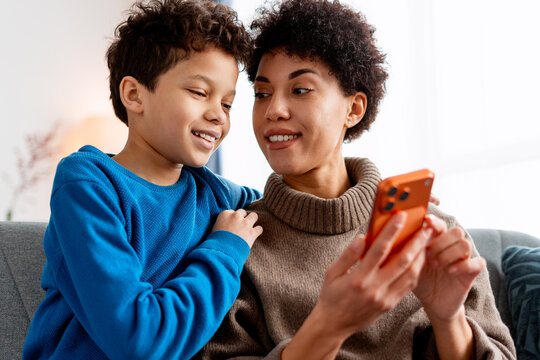 Happy multi ethnic mother and child spending bonding time using a mobile phone