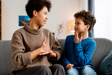 Mother and son communicating with sign language at home, fostering inclusion © Maria Vitkovska