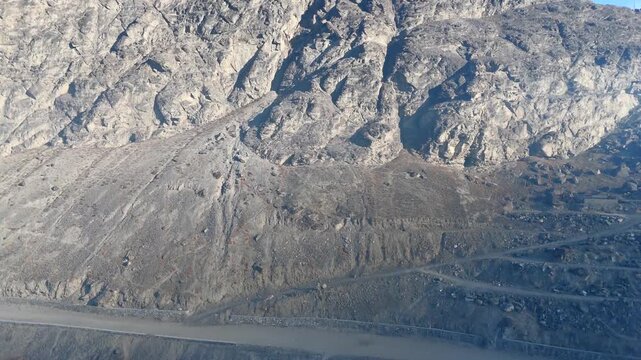 Aerial view of a stark, grey mountain face revealing textures of rock and shadow, creating a dramatic landscape, Skardu, Gilgit Baltistan, Pakistan.