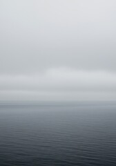 Fototapeta premium A thick layer of ethereal fog rolls across the gray, calm surface of the open ocean, obscuring the distant horizon line ,view ,mysterious ,water