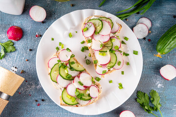 Naklejka premium Spring breakfast toasted bread sandwiches with cream cheese, radishes, cucumber and fresh herbs. Bruschetta sandwich for healthy diet vitamin snack 