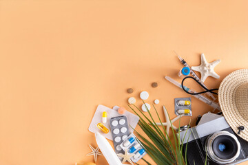 Obraz premium Summer holiday travel setup background including first aid kit with medications, pills, hat, and vacation accessories. Medication in journey, vaccinations, travel health insurance concept