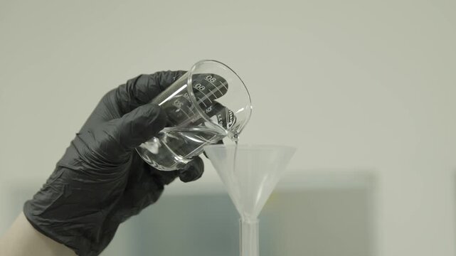 Beaker pouring liquid through funnel in laboratory 4k