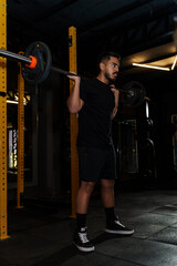 Strong Athletic Man Performing Barbell Back Squat in Modern Gym