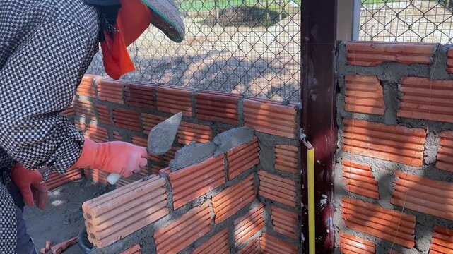 Bricklayer Applying Mortar While Building Brick Wall