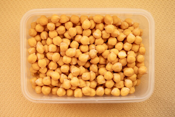 Top view of cooked chickpeas in a plastic container. Healthy plant protein ingredient for vegetarian meals and balanced diet cooking.