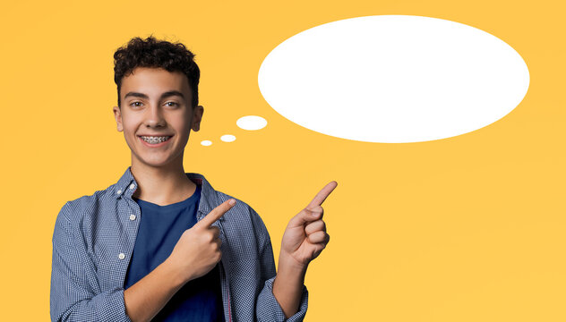 Happy smile black curly haired man in braces, wear blue denim shirt, t-shirt advertise point show free text space, isolated yellow background. Dental care ad concept. White mockup speech bubble