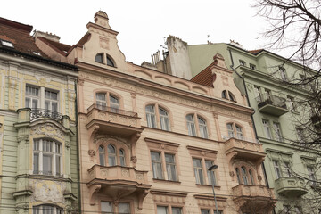 Obraz premium Pastel pink and green townhouses with decorative balconies and curved bay elements, ornate molding and balustrades create charming residential street scene, suited for lifestyle, travel