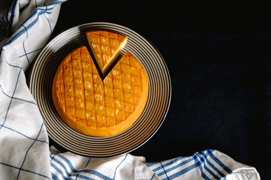 Fromage au lait de vache sur assiette avec une part coup&eacute;e, vu de dessus