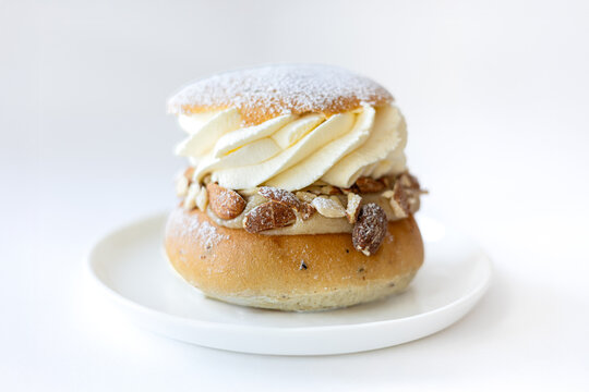 Swedish Semla pastry with whipped cream and almonds on a white plate