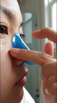 Woman face closeup skincare with blue patch eye and hand finger beauty, self care moisturizing healthy routine, using blue oil blotting paper for oily skin control, natural light bathroom reflection